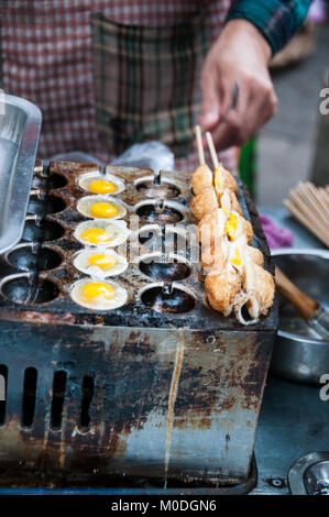 Frying quail eggs on a skewer as street food in the Muslim Quarter of Xi’an, China. One of a series of three. Stock Photo