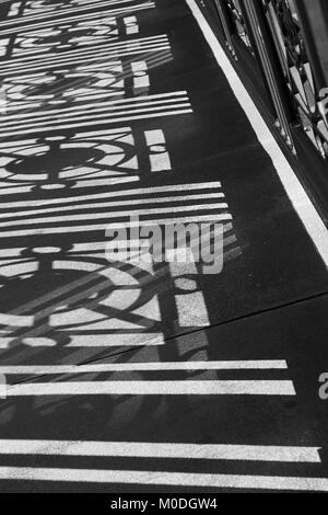 shadows cast on sidewalk formed by railing pattern Stock Photo