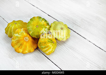 Five yellow and green bush pumpkins on white wood background left. Garden,agriculture and farming concept. Stock Photo