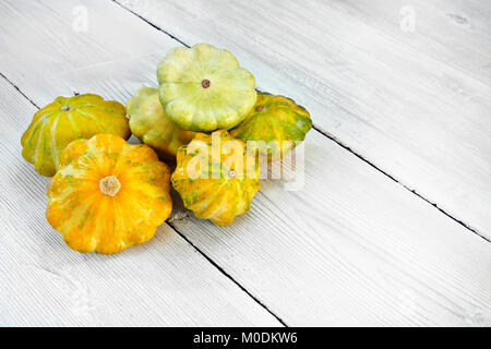 Five yellow and green bush pumpkins on white wood background. Garden,agriculture and farming concept. Stock Photo