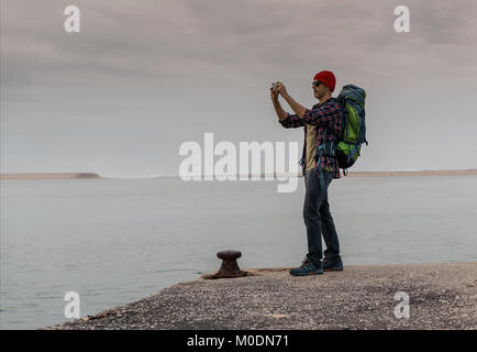 Man Traveling Backpack enjoying the beautiful view of the lake Stock Photo