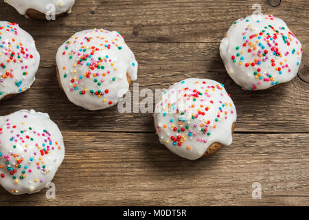 Easter pastry. Fresh Homemade Carrot Mini Cakes with White Creamy Sugar Icing and Colorful Decor over wooden background with copy space. Easter Cakes  Stock Photo