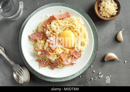 Spaghetti carbonara pasta with egg sauce, bacon and grated parmesan cheese  - homemade healthy italian pasta on grey concrete background Stock Photo