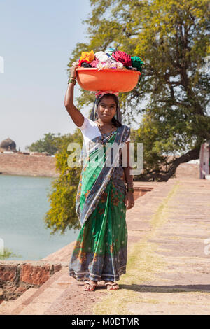 Poor young indian girl carrying clothes washing in a bundle on her