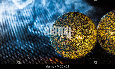 Detail of balls from black fibers on net and blue fume in background. Light trapped inside the spheres. Science fiction, fantasy, technology, industry. Stock Photo