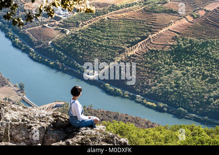 Girl practices yoga in the top of mountain overlooking the Douro River and valley of the best and world  renewed wineries of Portugal. Stock Photo