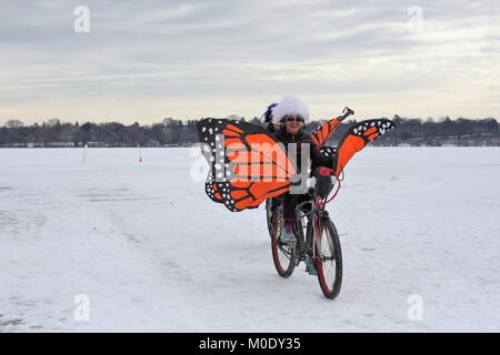 People riding a bicycle with butterfly wings on frozen lake harriet at the Art Shanty Projects on frozen Lake Harriet in Minneapolis, MN, USA. Stock Photo