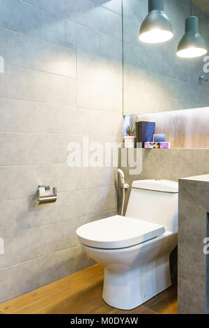 interiors shots of a modern bathroom in the foreground the shower with concrete floor and toilet bowl Stock Photo