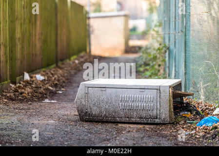 Fallen broken electrical box outdoors on footpath with cable wires exposed. Stock Photo