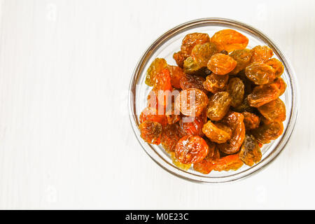 Golden Raisins from dried grapes in a glass bowl on sacking on a white wooden table of boards. Ingredients for cooking Stock Photo