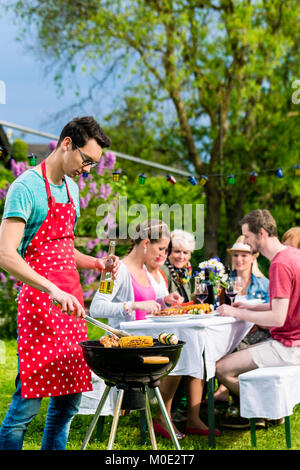 Man grilling meat on garden barbecue party Stock Photo