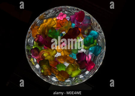 Multi-coloured Jelly sweets, in a crystal bowl that is backlit on a black background. Stock Photo