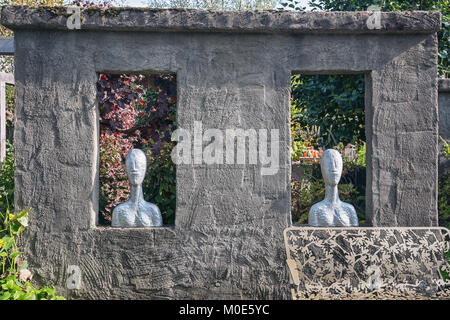 Apeltern, Netherlands, September 29, 2017: Two rectangular holes in the wall filled with two busts and in front an iron frog bench Stock Photo