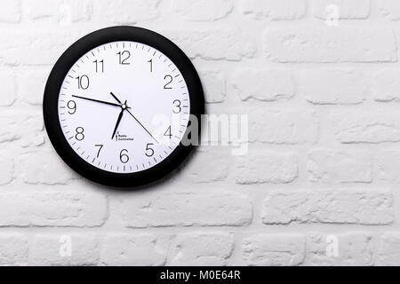 Wall clock on white brick wall with copy space Stock Photo