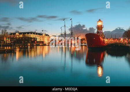 Amsterdam, Netherlands, December 16, 2017:  Lightship moored at the quay with in the background the Maritime Museum with VOC ship in Amsterdam Stock Photo