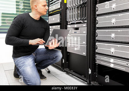 Consultant With Laptop Monitoring Servers In Datacenter Stock Photo