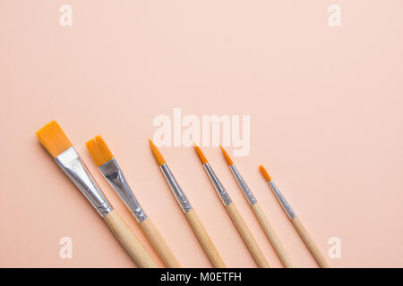 Bunch of Various Kinds of Paint Brushes on Light Pink Peachy Background. Copy Space for Artwork Lettering Calligraphy Text Inspirational Quote. Creati Stock Photo