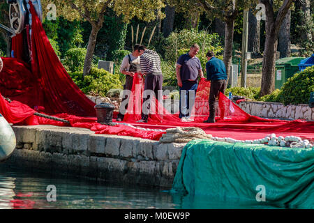 Fishermen mending nets on quayside, Krk, Croatia. May 2017. Stock Photo