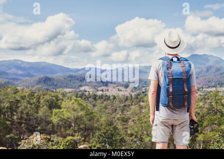 summer trekking in the mountains, tourist hiker travels outdoors, hipster with camera and backpack looking at panoramic landscape Stock Photo