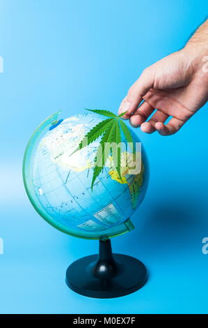 Hand holding cannabis leaf in front of a globe Stock Photo