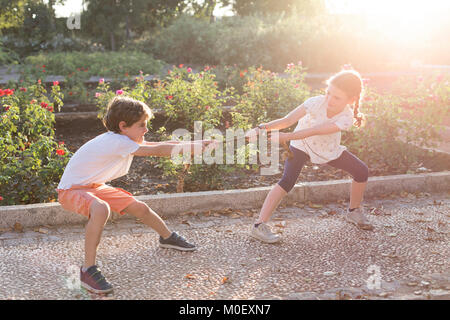 Boy and girl standing in garden pulling a rope Stock Photo