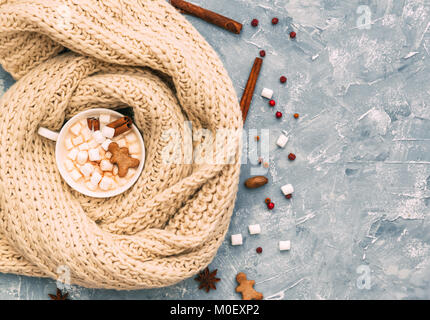 Hot chocolate with marshmallows, gingerbread man and Christmas spices wrapped in a knitted scarf Stock Photo