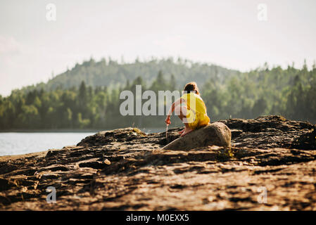 Young girl playing on rocks by a lake Stock Photo