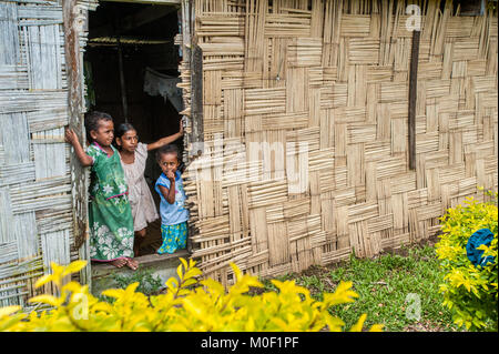 Three siblings look out the door of their home in a small remote village near Sigatoka on Viti Levu in the Fiji Islands. Stock Photo