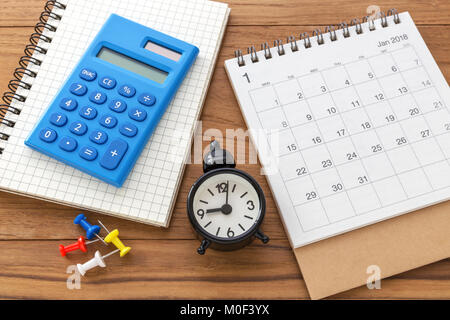 Calendar with calculator and clock on wooden table Stock Photo