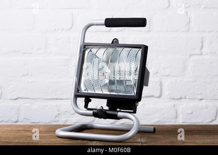 Construction light in front of brick wall on wooden board, closeup Stock Photo
