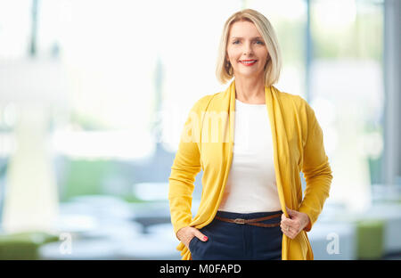 Beautiful senior businesswoman wearing casual clothes and looking at camera while standing at the office. Stock Photo