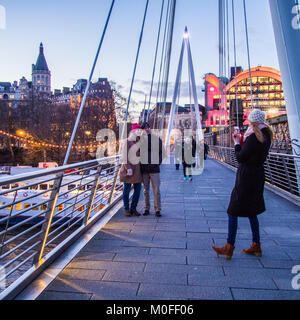 People posing for a photo on Golden Jubilee Bridge London. Hungerford railway bridge is on the right & Charing Cross station in the background. Stock Photo