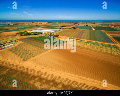 Aerial view of plowed fields and crops near ocean coastline on bright summer day. Werribee South, Victoria, Australia Stock Photo