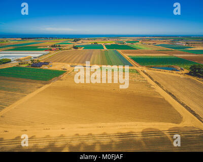 Scenic aerial landscape of plowed fields and crops near ocean coastline on bright summer day. Werribee South, Victoria, Australia Stock Photo