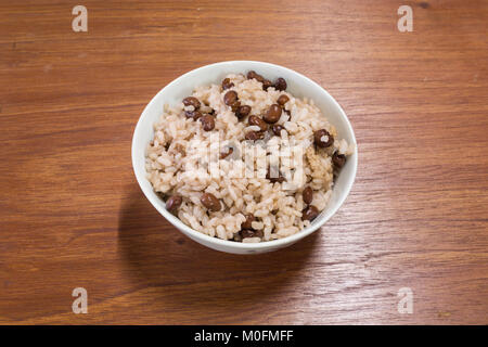Cooked red beans and Japanese rice in white bowl on wooden table