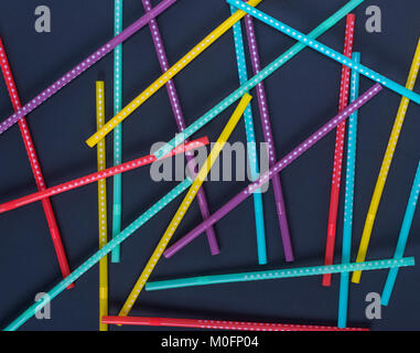 multi-colored plastic tubes in a white polka-dot for drinks are scattered on a black background Stock Photo