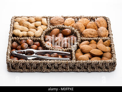 Basket reach in various kinds of nuts in shells, pecans, almonds, hazelnuts, peanuts and walnuts on white background Stock Photo