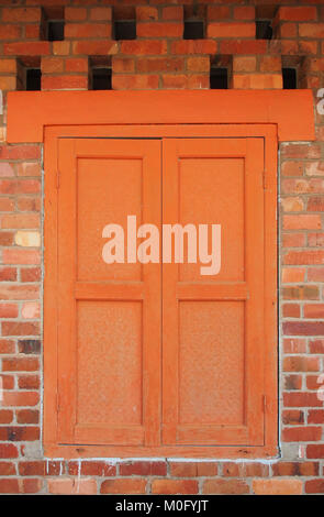 Orange window on red brick wall, Batu Arang, Malaysia Stock Photo