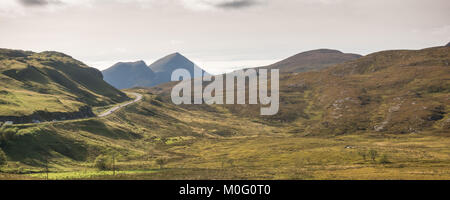 The A835 road, part of the North Coast 500 touring route, winds past Knockan Crag at Elphin in Assynt, with Cul Beag mountain rising behind. Stock Photo