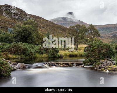 The mountain Stac Pollaidh rises into the clouds behind the River Polly in the Assynt district of the Northwest Highlands of Scotland. Stock Photo