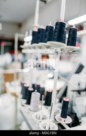 Black threads on spools closeup, overlock machine, sewing material, yarn on bobbins macro, tailoring or dressmaking equipment Stock Photo