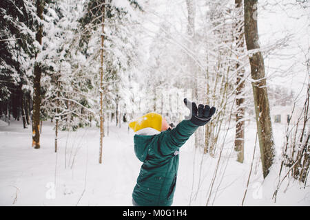 Teenage boy throws handfuls of snow into the air and enjoys it falling on his face. Stock Photo