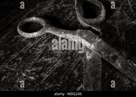 Pair of old, rusty scissors on scratched wooden table-top. Stock Photo