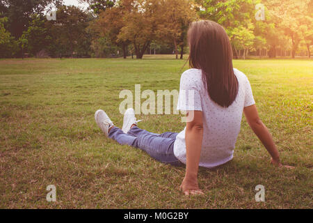 Woman relaxing and lies on green grass in the park in vintage style ...