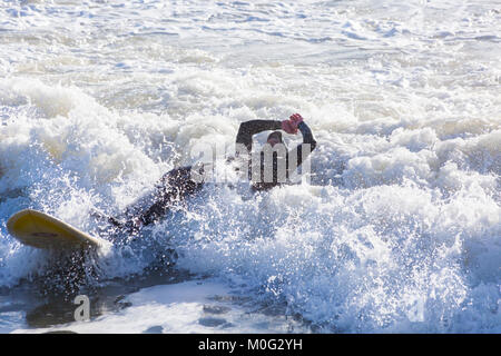 Surfer falling off of surf board, making the most of the large waves and choppy seas at Bournemouth, Dorset UK in January Stock Photo
