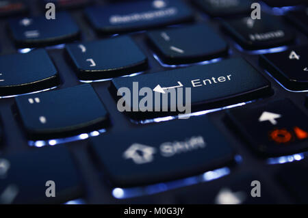 Sharpened enter key on the black, white led highlighted notebook keyboard Stock Photo