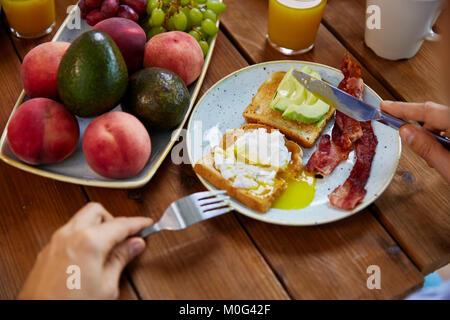 man eating toast with pouched egg and bacon Stock Photo
