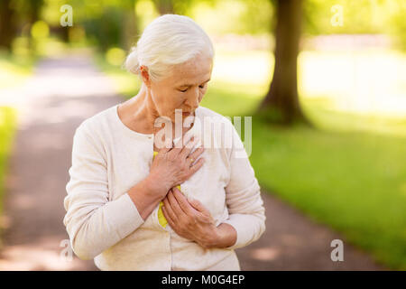 senior woman feeling sick at summer park Stock Photo