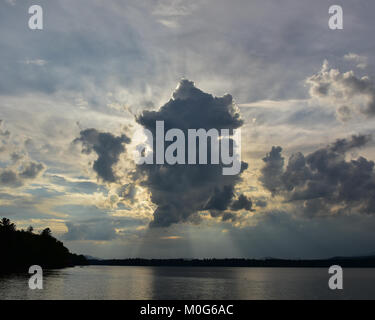 Storm clouds over Lake Pleasant in the Adirondack Mountains blocking the evening sun.. Stock Photo
