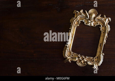 antiq golden photo frame in Rococo style, on dark rustic wooden background Stock Photo